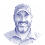 A Man Wearing A Hat And Smiling At The Camera